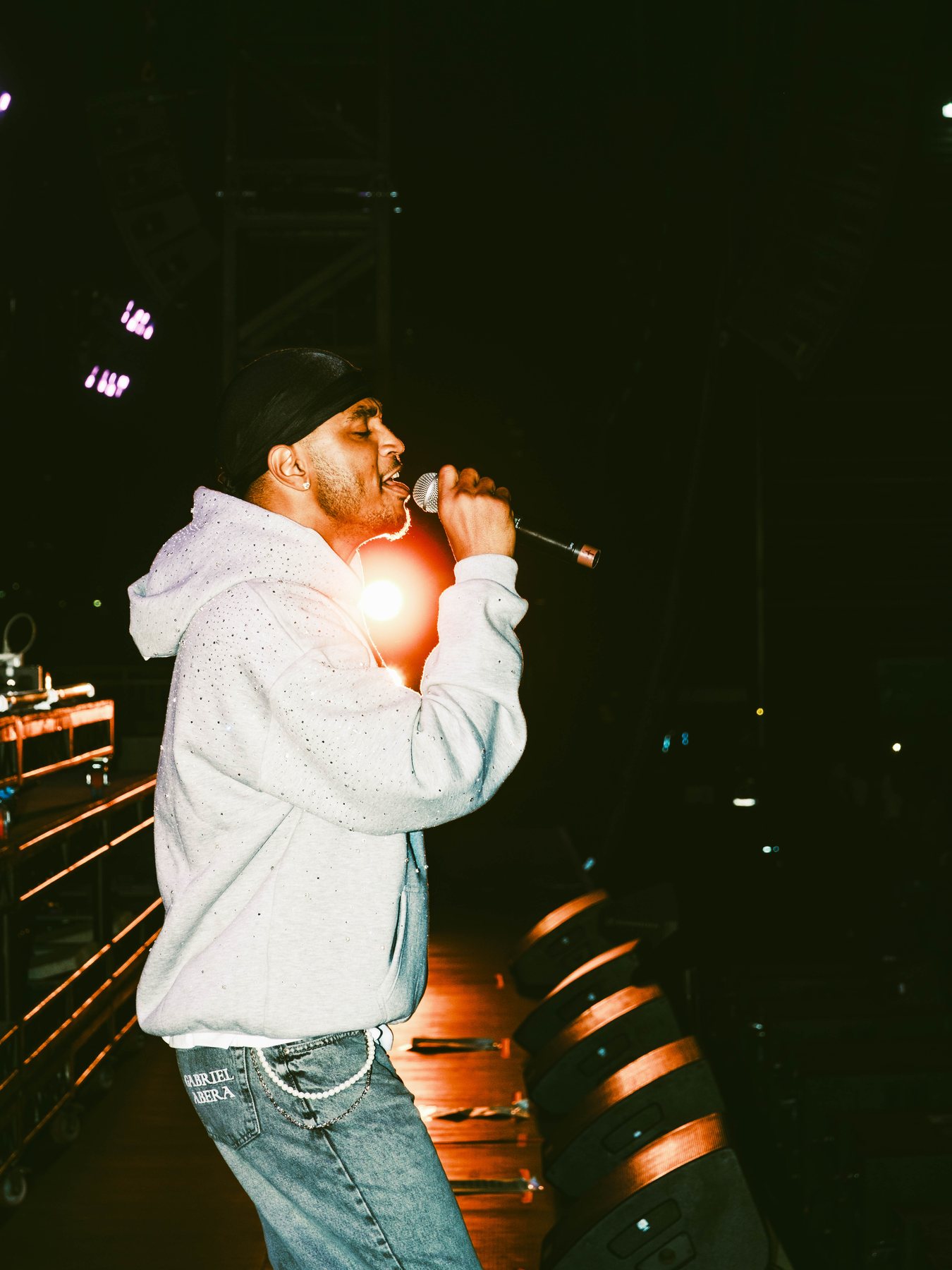 Odeal singing into a handheld microphone under warm stage lighting.